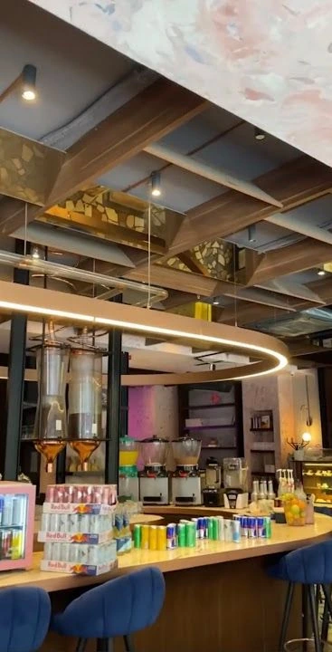 What The Coffee Akaretler'de bar tezgâhı, mavi sandalyeler ve dairesel tavan aydınlatması